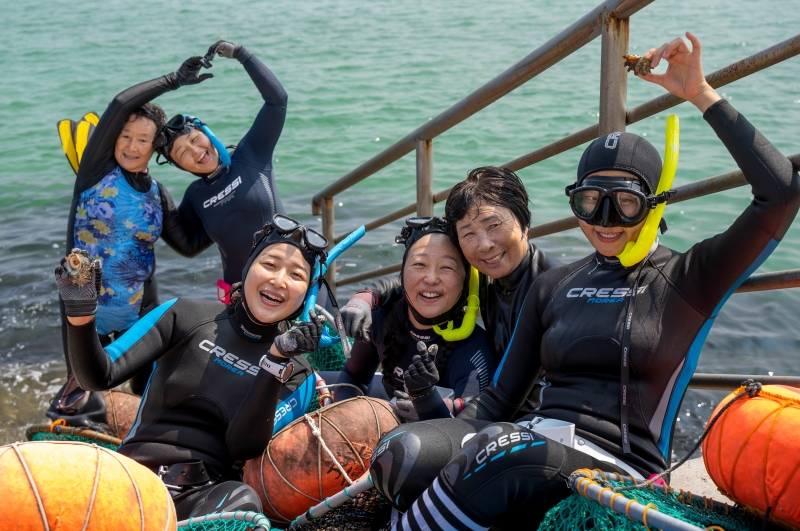 Participants in a four-day haenyeo (female diver) interactive program and course instructors on Sept. 8 pose with the top shells they collected. (Kim Da Eun)