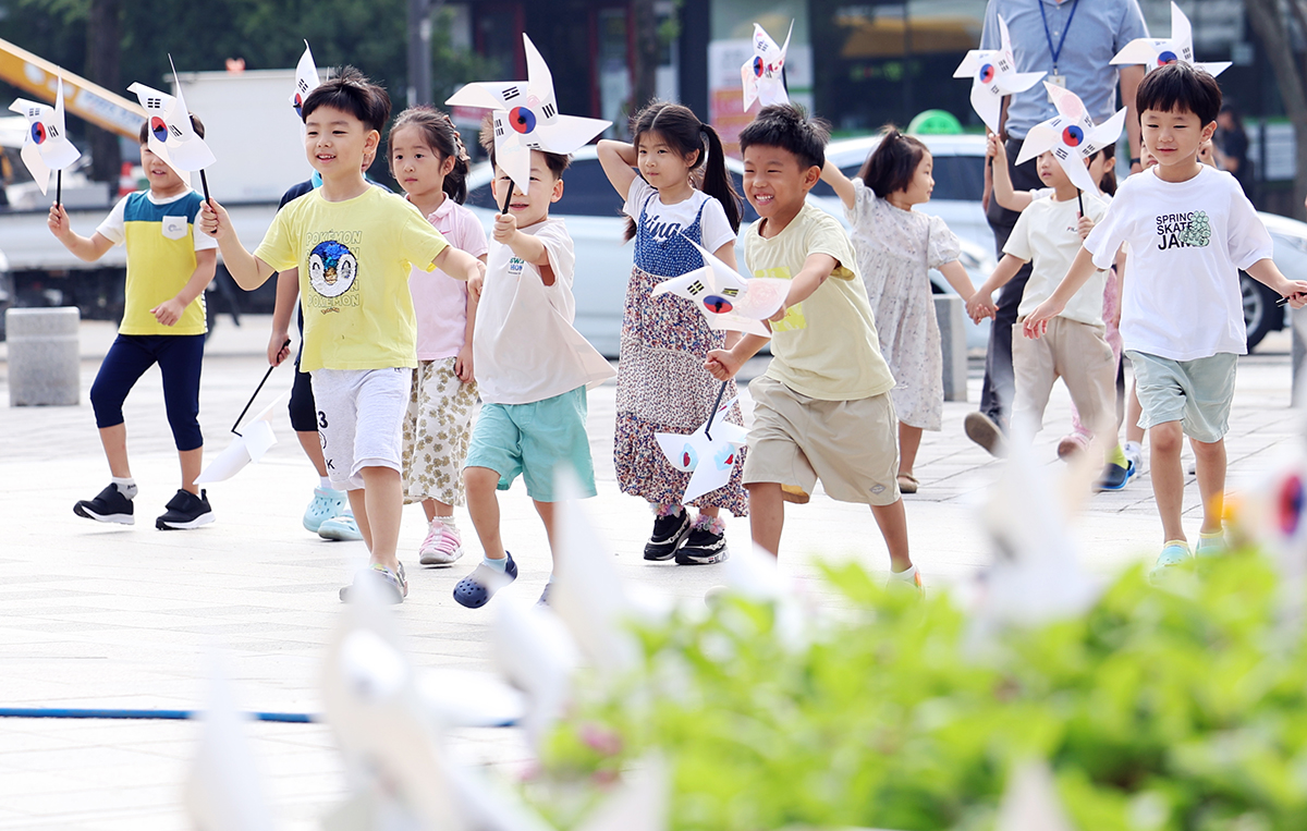 Children from the daycare center of Gwangju's Buk-gu District on Aug. 14, the day before the 78th National Liberation Day, run with pinwheels displaying the national flag Taegeukgi at the district office's plaza.