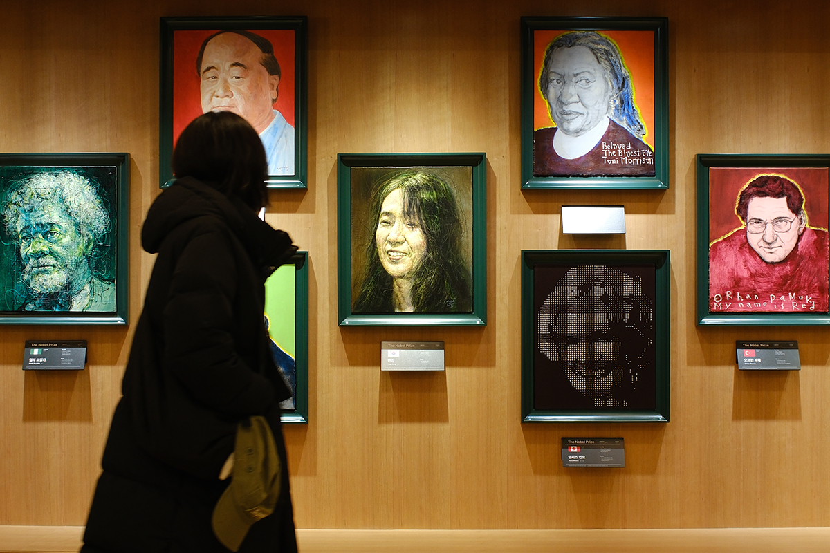 A visitor to the Gwanghwamun branch of Kyobo Bookstore in Seoul on Dec. 10 looks at the face of Han Kang in an exhibition of portraits of Nobel Prize laureates.